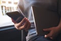 A woman using and looking at a black smart phone while holding laptop computer Royalty Free Stock Photo