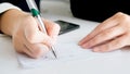 Closeup image of woman writing signature on banking cheque Royalty Free Stock Photo