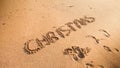 Closeup image of word Christmas inscripted on sandy beach. Footaprints on wet sand. Concept of winter holidays, New Year Royalty Free Stock Photo