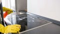 Closeup image of young housewife spraying detergent on electric hob