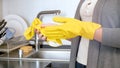 Closeup photo of young housewife taking off yellow latex gloves after washing dishes Royalty Free Stock Photo