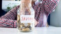 Closeup photo of young man emptying glass jar full of coins Royalty Free Stock Photo