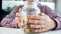 Closeup photo of young man holding glass jar full of coins Royalty Free Stock Photo