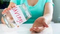 Closeup photo of young woman having financial problems emptying glass jar with money savings Royalty Free Stock Photo