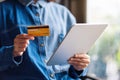 A young woman holding credit card while using tablet pc Royalty Free Stock Photo