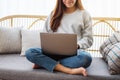 A young woman using and working on laptop computer while sitting on a sofa at home Royalty Free Stock Photo