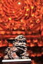Closeup of an imperial guardian lion Chinese lion wooden statue inside a temple with blurred background.
