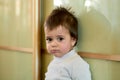 Closeup indoor portrait of a baby boy with naughty hair. The various emotions of a child.