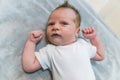 Closeup indoor portrait of a european infant baby boy in light blue bodysuit clenching his fists and giving a surprised Royalty Free Stock Photo