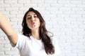 Closeup indoor portrait of stunning pretty girl making selfie, blue cap and printed dress, sportive trendy style, funny positive e Royalty Free Stock Photo