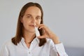 Closeup indoor shot of charming woman using nasal spray for runny nose, catches cold, looking at camera, wearing white shirt, Royalty Free Stock Photo