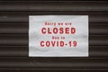 Information sign on the metallic shutter of the store front : Sorry we are Closed due to covid-19