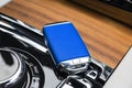 Closeup inside vehicle of wireless blue leather key ignition on natural wood panel. Wireless start engine key. Car key remote isol Royalty Free Stock Photo