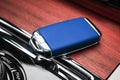 Closeup inside vehicle of wireless blue leather key ignition on natural wood panel. Wireless start engine key. Car key remote isol Royalty Free Stock Photo