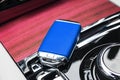 Closeup inside vehicle of wireless blue leather key ignition on natural wood panel. Wireless start engine key. Car key remote isol Royalty Free Stock Photo