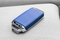 Closeup inside vehicle of wireless blue leather key ignition on white leather seat. Wireless start engine key. Car key remote isol