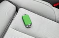 Closeup inside vehicle of wireless green leather key ignition on white leather seat. Wireless start engine key. Car key remote iso Royalty Free Stock Photo