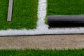 Closeup installation of football field with artificial turf with grass. Close up of line of an artificial football field. Details