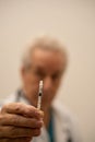 Closeup of an insulin SHot needle with blurry doctor in background