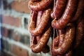 closeup of interlinked sausages hanging near a brick wall