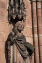 Closeup of intricately carved stone statue mounted above a brick wall in Lichfield Cathedral, UK