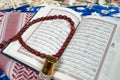 Closeup of Islamic book Quran rosary and shemagh scent bottle on colorful prayer mat,religious
