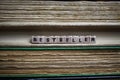 Closeup of isolated antique old book pile text blocks and yellowed pages with wooden alphabet cubes forming word bestseller