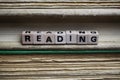 Closeup of isolated antique old book pile text blocks and yellowed pages with wooden alphabet cubes forming word reading Royalty Free Stock Photo