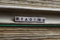 Closeup of isolated antique old book pile text blocks and yellowed pages with wooden alphabet cubes forming word reading Royalty Free Stock Photo