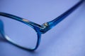 Closeup of isolated blue eyeglass lens with earpiece hinge on blank background