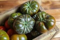 Closeup of isolated group dark black beef cabomar tomatoes in rustic wood box, brown wooden planks background Royalty Free Stock Photo