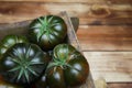 Closeup of isolated group dark black beef cabomar tomatoes in rustic wood box, brown wooden planks background Royalty Free Stock Photo