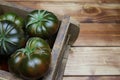 Closeup of isolated group dark black beef cabomar tomatoes in rustic wood box, brown wooden planks background Royalty Free Stock Photo