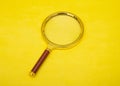 Closeup of isolated magnifying glass on yellow background