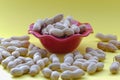 Closeup on isolated peanut nuts in a red bowl on the yellow background