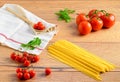Closeup of Italian pasta with vine and cherry tomatoes on wooden board Royalty Free Stock Photo