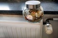 Closeup of a jar full of coins on a heating radiator Royalty Free Stock Photo