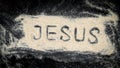 Closeup of JESUS word written on white sand