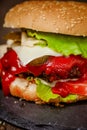 Closeup juicy beef burger with fresh vegetables on stone board. Homemade cooking