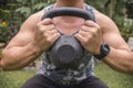 Closeup of a kettlebell used for goblet squats by an unidentifiable man outdoors