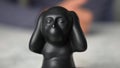 Closeup of Kikazaru monkey statue who hears no evil and a gesticulating man in the background