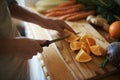 Closeup, kitchen and fruits with hands, orange or wood board with knife, vegetables or salad. Person, vegan or chef with Royalty Free Stock Photo