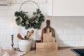 Closeup of kitchen interior. Christmas decoration. Advent floral hoop wreath hanging on peg rails. White brick wall Royalty Free Stock Photo