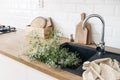 Closeup of kitchen interior. White brick wall, metro tiles, wooden countertops with chopping boards. Cow parsley plants