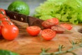 Closeup kitchen knife, sliced tomatoes on wooden cutting board indoors