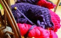 Closeup of knitted colorful purple pink blanket, ball of raw merino wool, knitting needles with old retro wooden spinning wheel Royalty Free Stock Photo