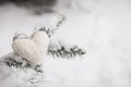 Closeup of knitted heart Christmas decoration on a Christmas tree with snow outdoors. Celebration, winter concept