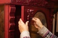 Closeup of lady hands attaching newly carved amazing wooden ornaments to red cardboard in workshop for furniture