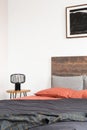 Closeup of lamp on wooden nightstand and black poster on the white wall of elegant bedroom interior with king size bed with wooden Royalty Free Stock Photo