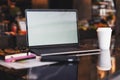 Closeup of laptop with blank monitor and cup of coffee on table in cafe. Empty workplace without people. Home office freelancer